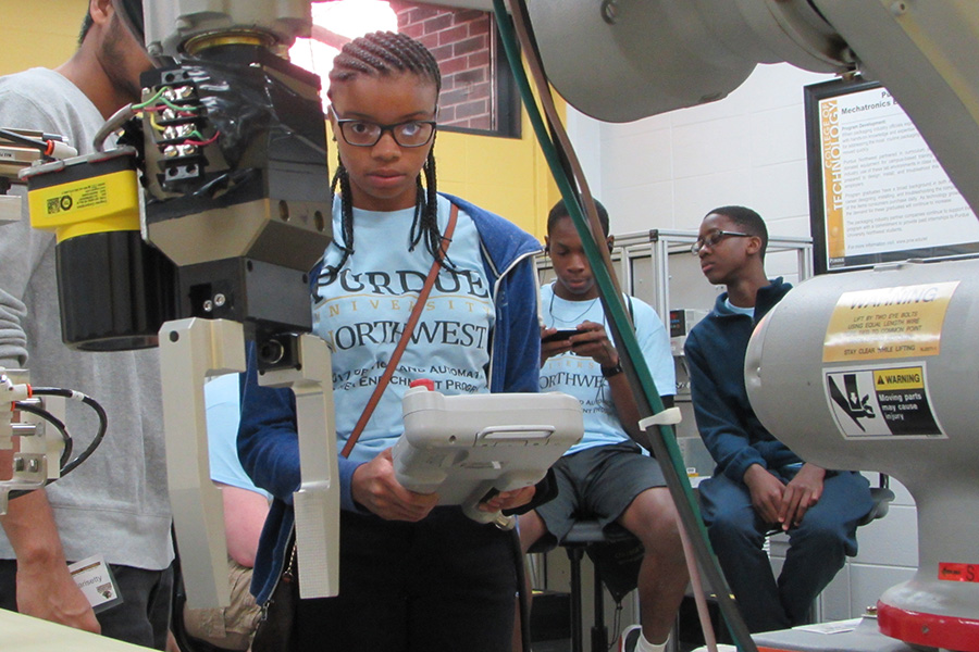 A young woman operates an industrial robot