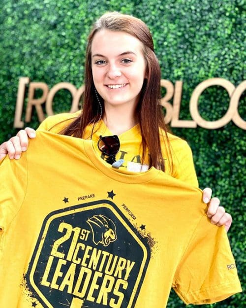 A student holds a 21st century leaders shirt.