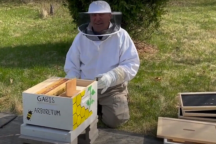 A beekeeper poses with a hive.