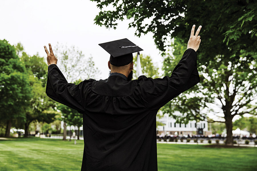 A PNW graduate raises two fingers on each hand.