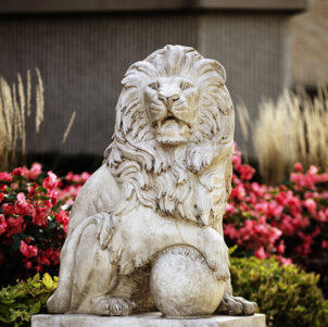A lion statue in front of flowers