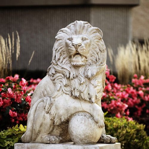 A lion statue in front of flowers