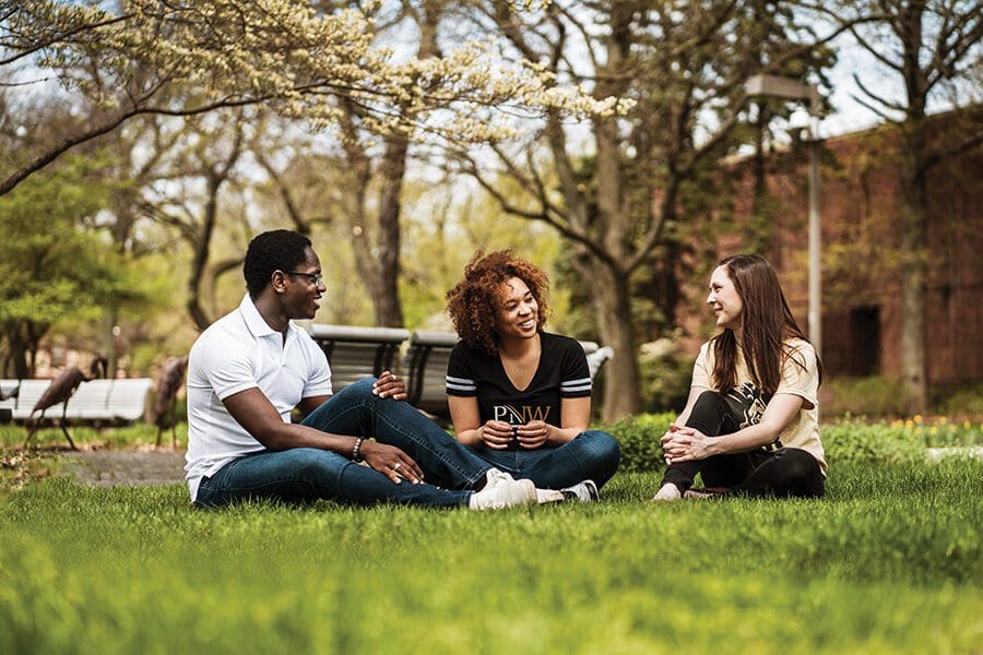 Students sit outdoors on a lawn