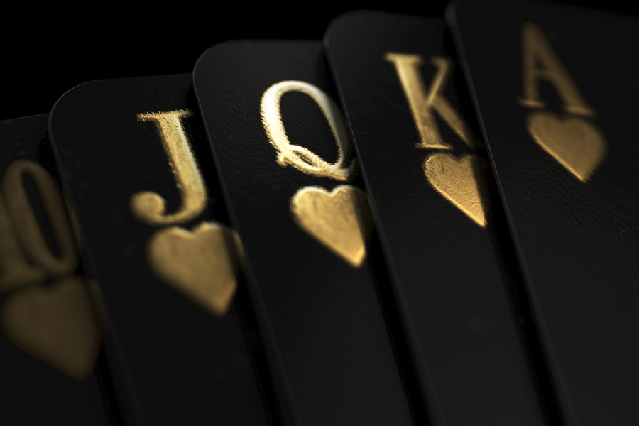 A fanned out royal flush suit of five black casino playing cards with gold markings on a dark classy background - 3D render
