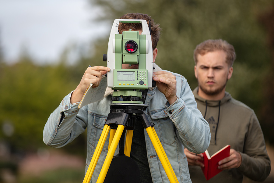 A student practices with surveying equipment.