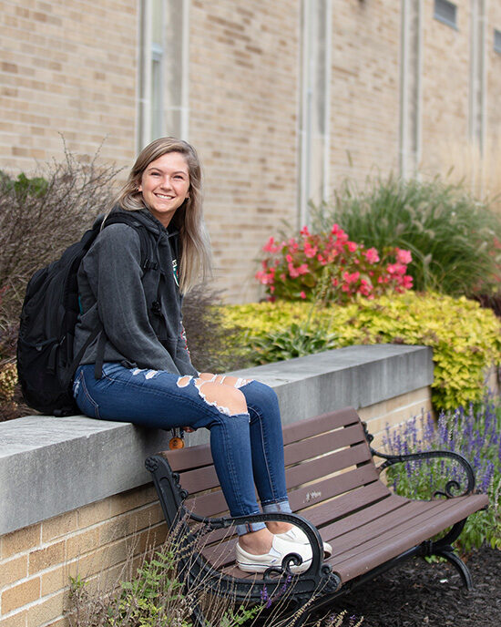 A student sits near flowers on PNW's Westville campus