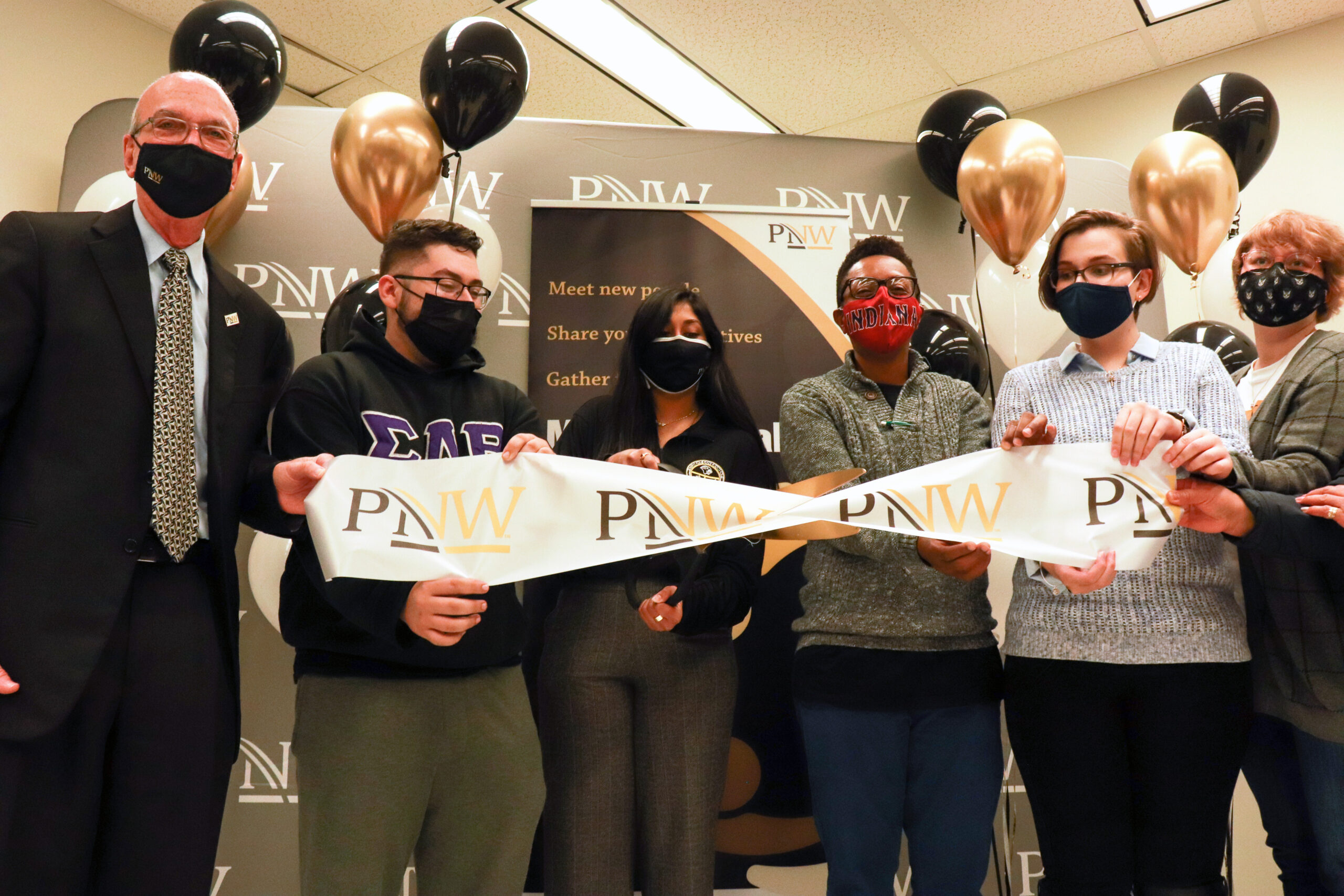 From left, Purdue University Northwest (PNW) Chancellor Thomas Keon, PNW students Luis Gamble and Aneri Patel, PNW Upward Bound administrative assistant Shanika Person, and PNW students Marisa Gorski and Micaela McCarthy perform a ceremonial ribbon cutting for the multicultural lounge.