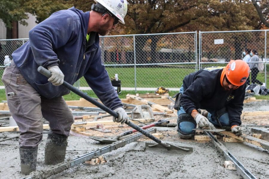 Larson-Danielson construction workers smooth out freshly poured concrete on Nov. 9 as they mold the base for a new campus bell tower.