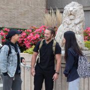Students talk beneath a lion sculpture