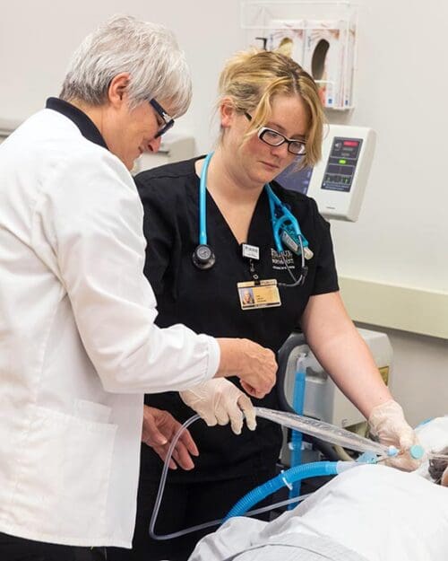 A PNW nursing instructor works with a student in a simulated care environment.