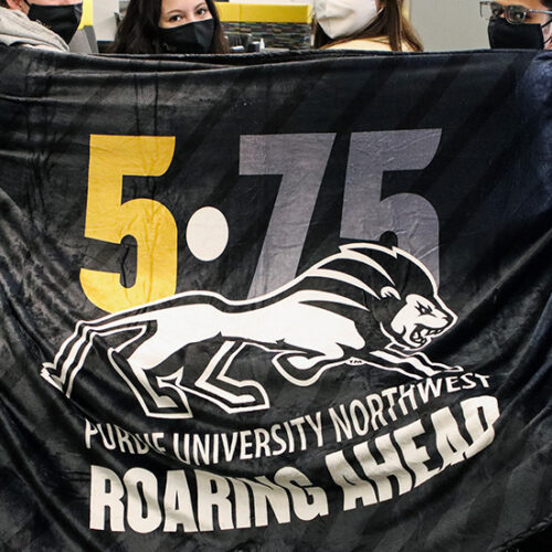 Students holding a blanket that says 5-75 Roaring Ahead