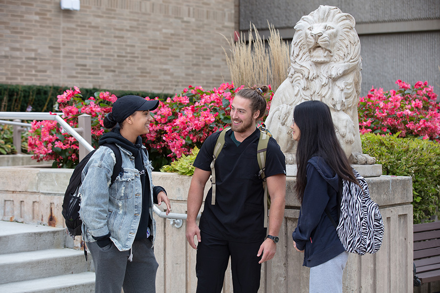 Students stand beneath a lion statue on PNW's Westville campus
