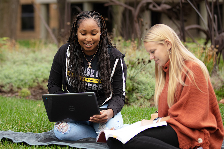 PNW students outdoors collaborate on a laptop