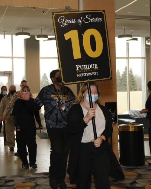 Line of people follow a person holding a sign.