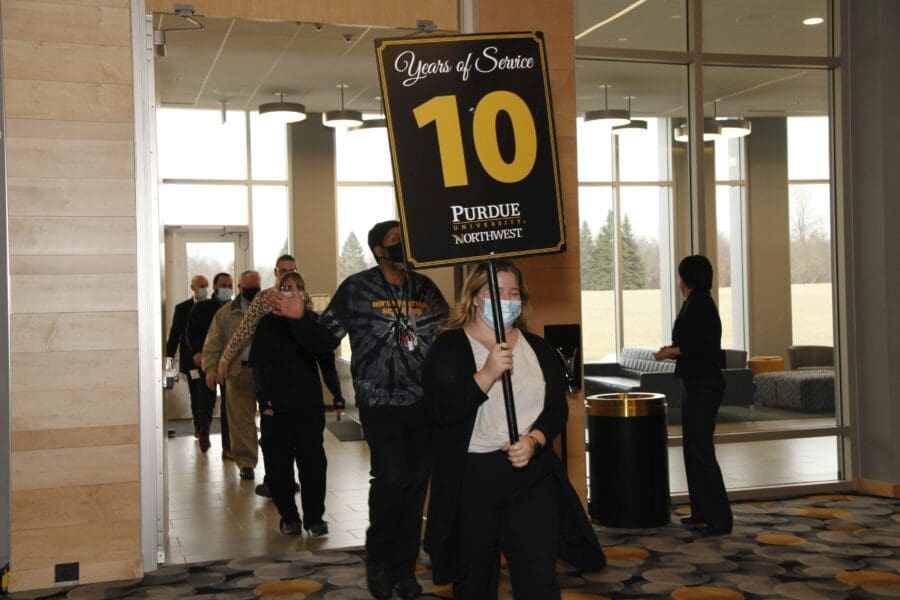 Line of people follow a person holding a sign.