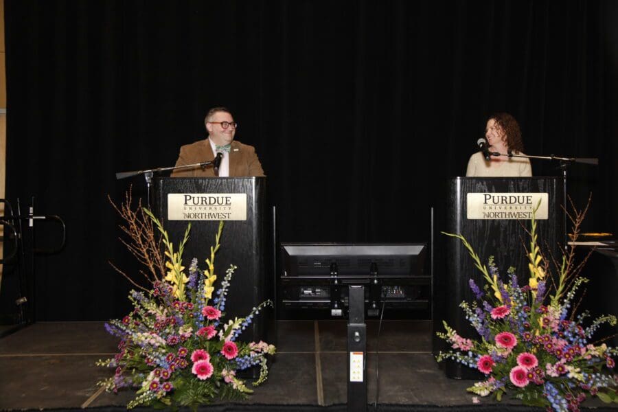 Two spokespersons stand to speak before crowd.