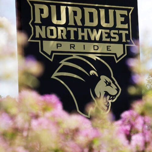 A Purdue Northwest Pride sign surrounded by flowers