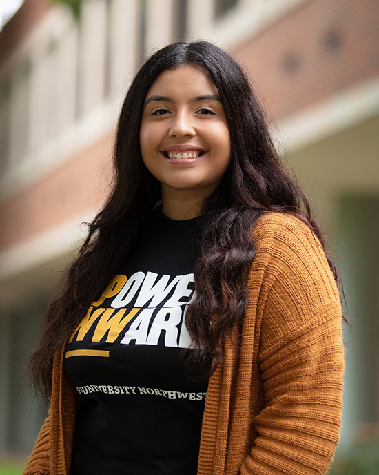 A Purdue University Northwest student stands outdoors in a Power Onward t-shirt.