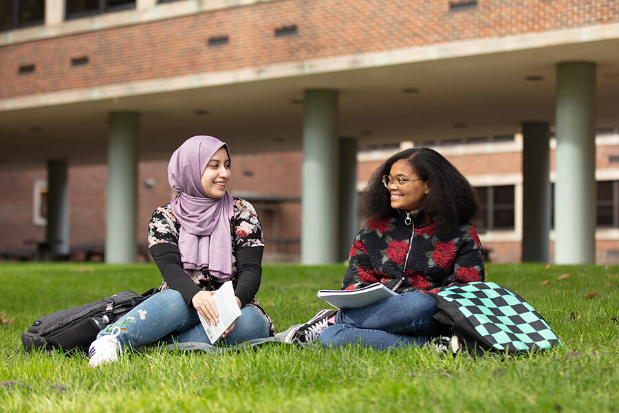 Two PNW students sit together on the grass.