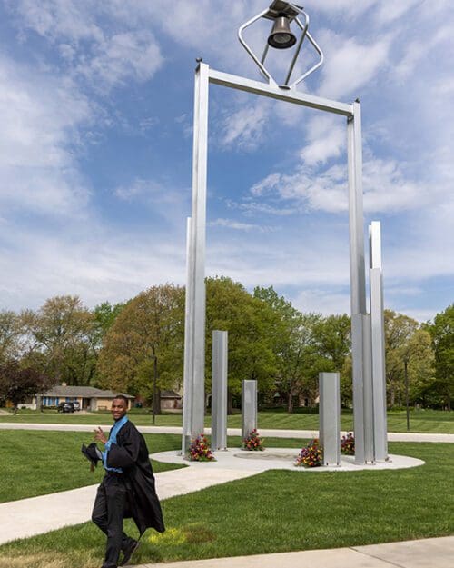 PNW student walking by the bell tower during commencement