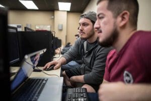 Students sitting in front of a computer monitor