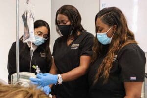 Three women in masks preparing an IV bag