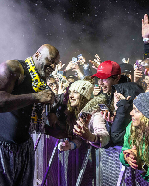 Students cheering and reaching over barricade taking photos with DJ Diesel (AKA Shaquille O'Neal)