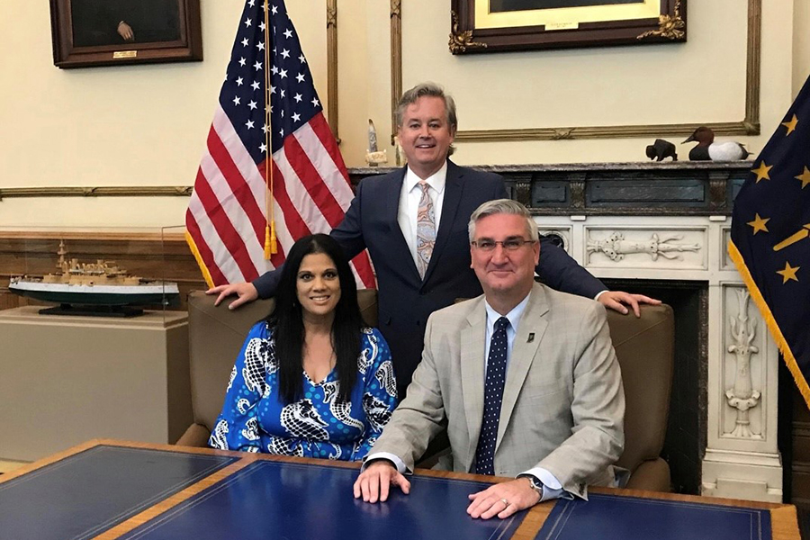 Nicky Jackson, Ralph Jackson and Governor Eric Holcomb posing at a desk