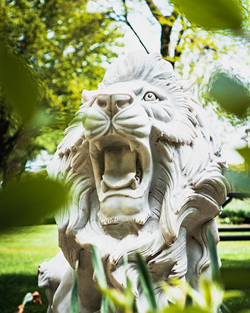 A lion sculpture surrounded by greenery.