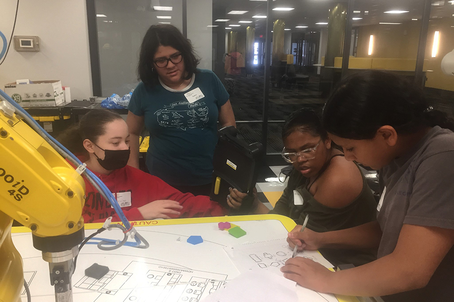 Four students circle around a group project