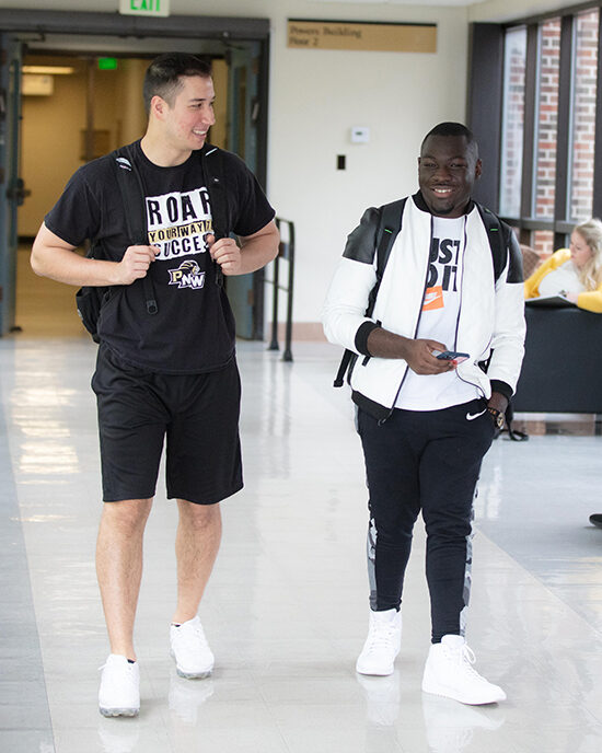 Two students walking together down a hallway