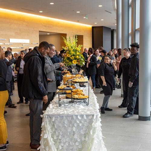 People stand around a table of food during a Founders Day event