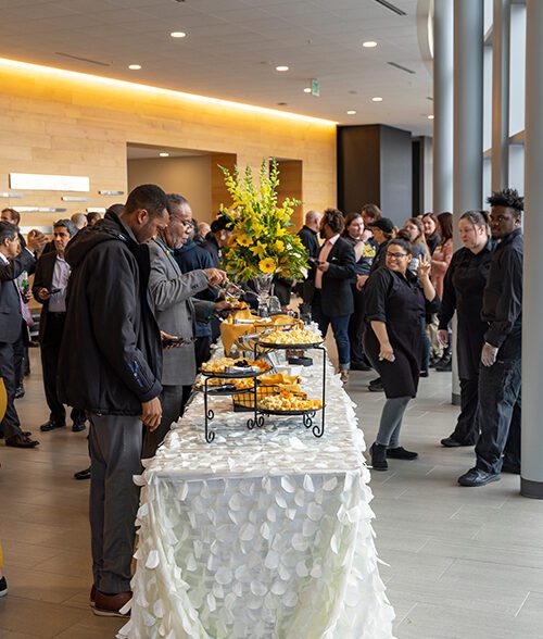 People stand around a table of food during a Founders Day event