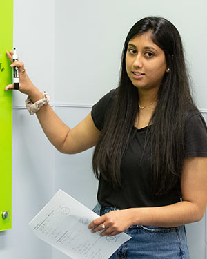 Student stands in front of a green dry erase board