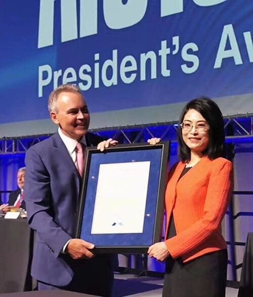 CIVS Director Chenn Zhou poses with another person and a framed award certificate