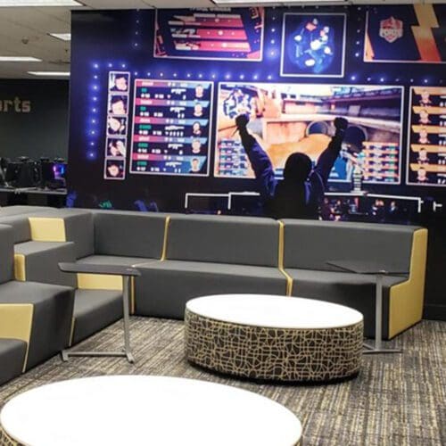 A student raises his arms before a large screen in PNW's eSports arena.