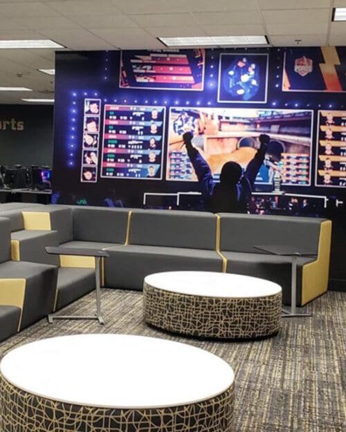 A student raises his arms before a large screen in PNW's eSports arena.