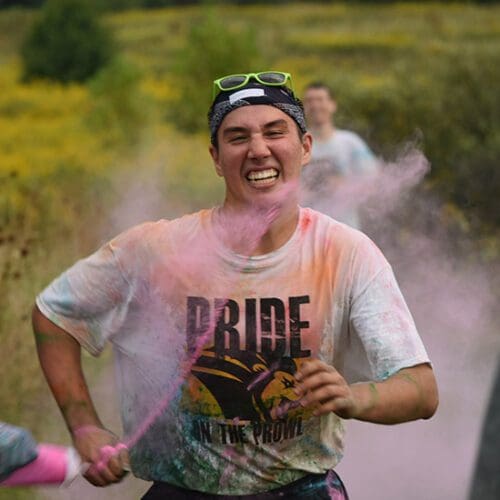 Pride Stride participant running and getting pink color powder sprayed at them