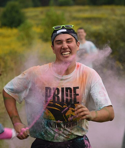 Pride Stride participant running and getting pink color powder sprayed at them