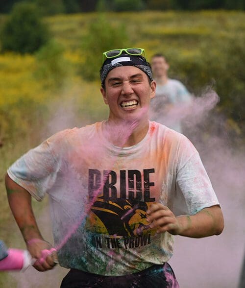 Pride Stride participant running and getting pink color powder sprayed at them