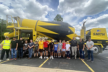 Campers and employees of Smith Ready Mix stand in front of a concrete mixing truck