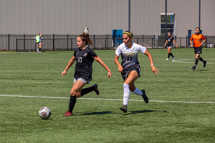 Women's soccer players run down a field during a practice game