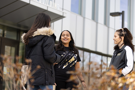 Three students talk together outside of the Nils K. Nelson Bioscience Building