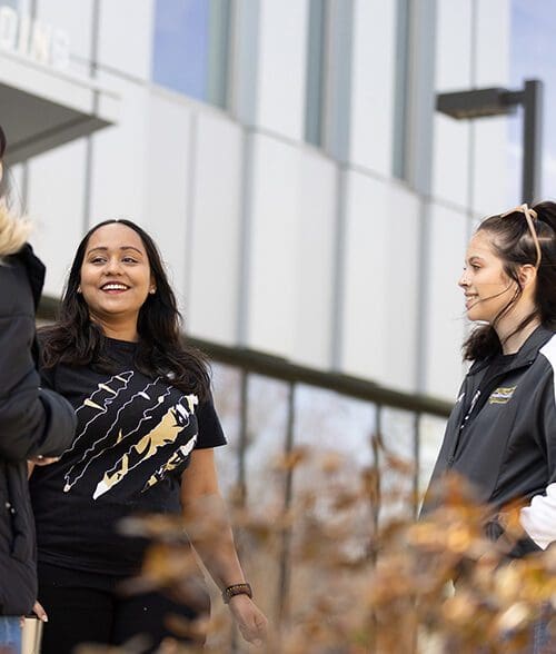 Three students stand together outside of the Nils K. Nelson Bioscience building