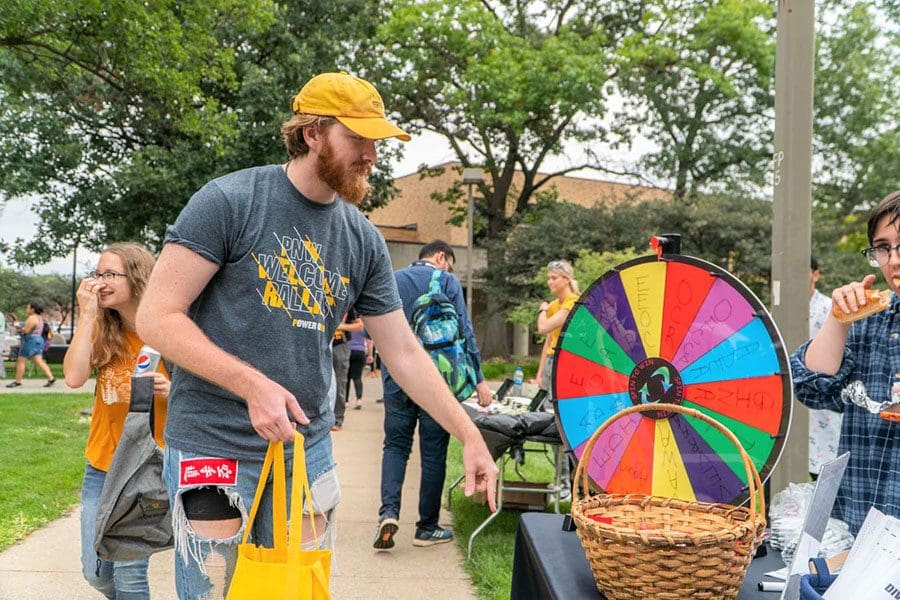 Students visit a table with a spinner wheel and basket on it