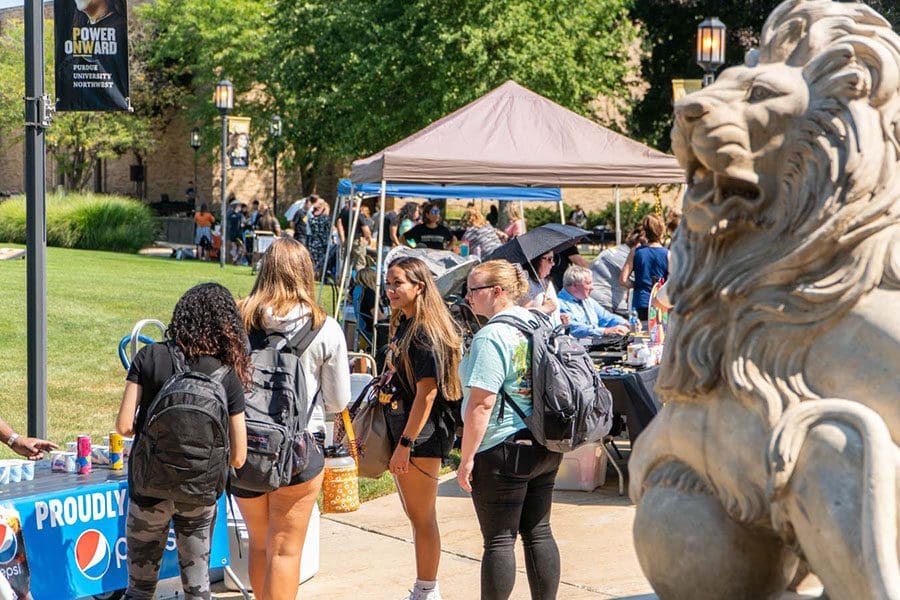 A group of students stands in front of a tent during Westville's welcome rally