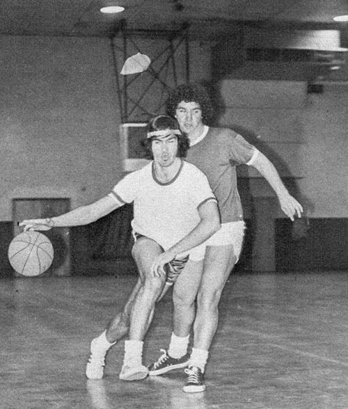 Two students play basketball. The photo is black and white