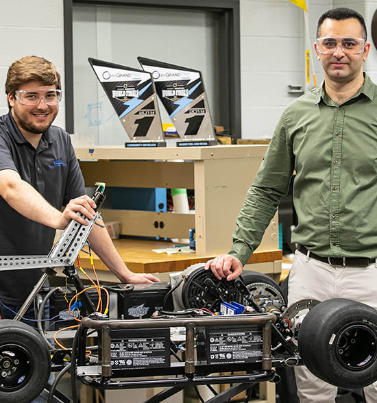 Andrew Miloshoff, standing on the left, and Khair Al Shamaileh work on an evGrand Prix vehicle.