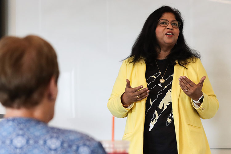 Neeti Parashar stands in the front of a class room talking.