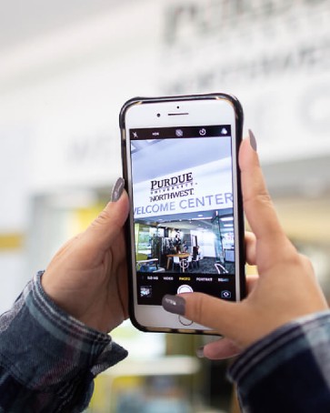 student holding cellphone with PNW image on it